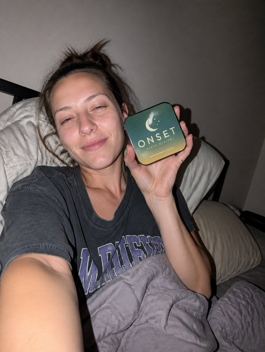 Person in bed at night holding an Onset Sleep Strips tin